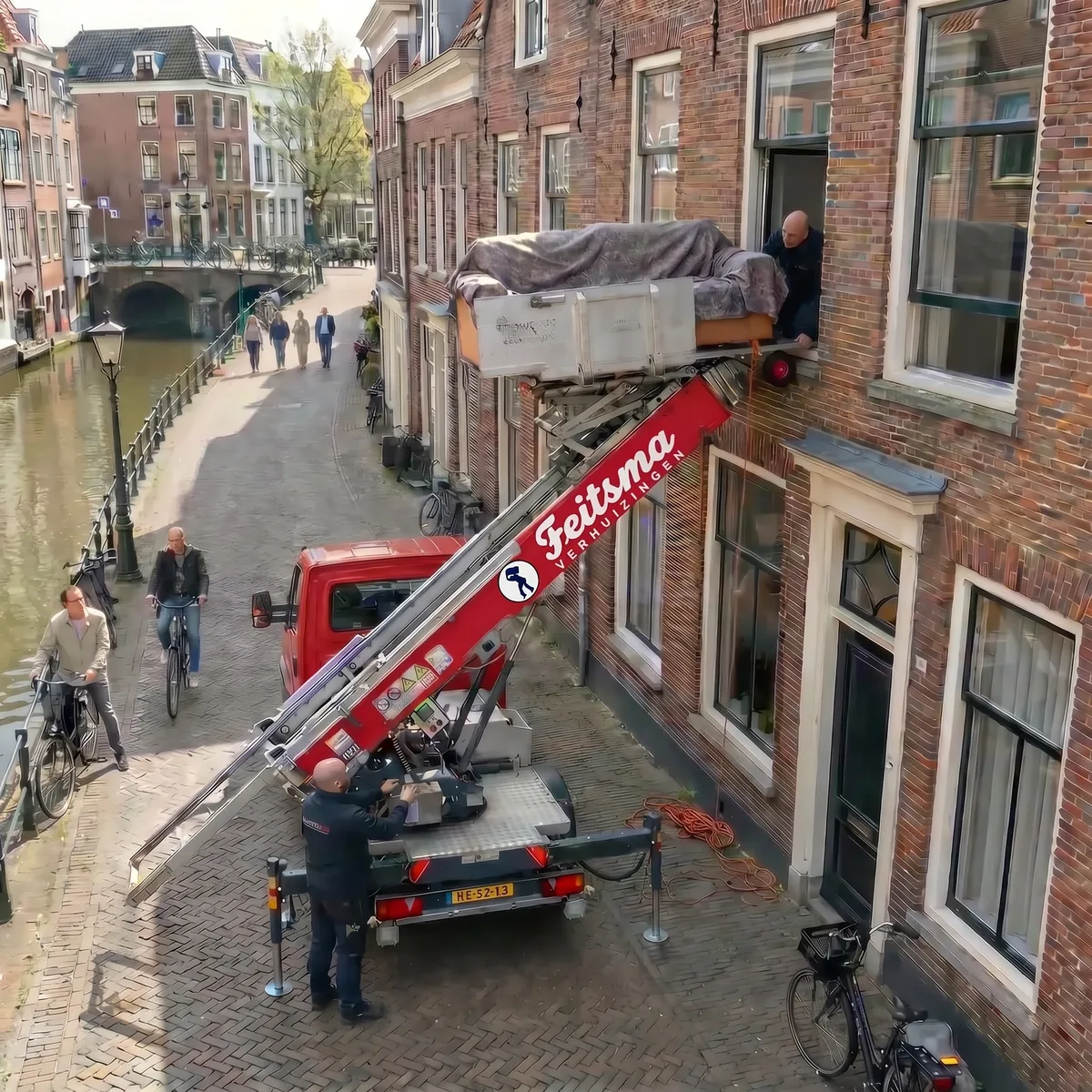 Feitsma-verhuislift aan de gevel van een grachtenpand met een bank op het plateau