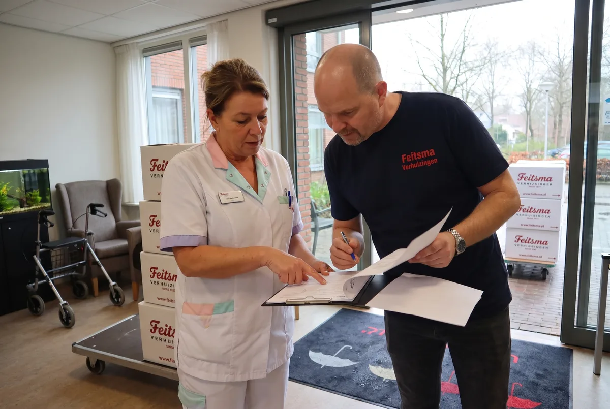 Voorman neemt het verhuisschema door met de zorgcoordinator in de hal