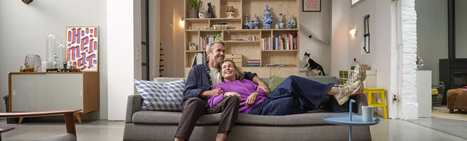 Stel zit ontspannen op de bank in hun nieuwe woning; campagnebeeld van Erkende Verhuizers
